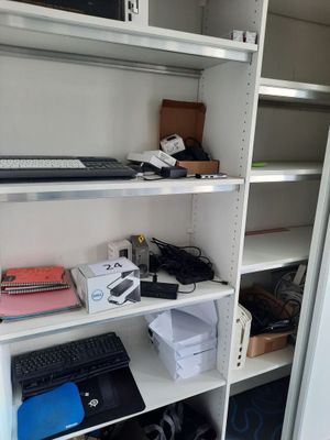 une étagère blanche sur laquelle se trouvent un ordinateur portable et d'autres appareils électroniques