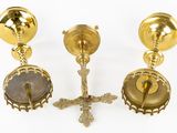 three brass candlesticks and a cross on a white background