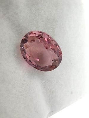 a pink oval shaped diamond on a white surface
