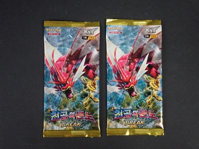 Deux paquets de cartes à collectionner Pokémon sont posés sur une table.