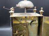 a small silver clock with a bell on top of it