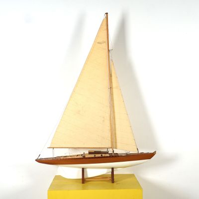 une petite maquette de voilier posée sur un socle jaune