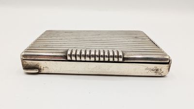 un petit étui à cigarettes argenté, muni d'une poignée en métal sur un fond blanc