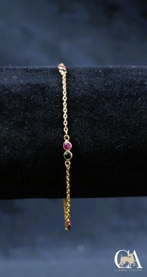 un bracelet en or avec une pierre rose et une chaîne