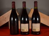 three bottles of red wine sit on a table next to a wooden box