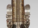 a silver and gold candle holder on a wooden stand