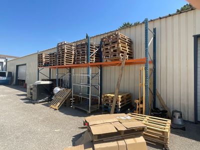 Plusieurs palettes de bois sont empilées devant un bâtiment