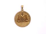 a close up of a gold pendant with a ship on it