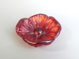un objet en forme de fleur rouge sur une surface blanche
