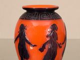 an orange vase with black figures on it on a table