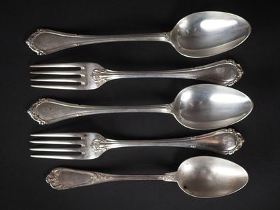 quatre cuillères en argent et une fourchette sur fond noir