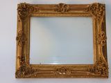 un cadre doré ancien avec un miroir accroché à un mur blanc
