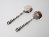 two silver spoons with handles and a handle on a white surface