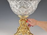a person that is holding a glass bowl on a stand