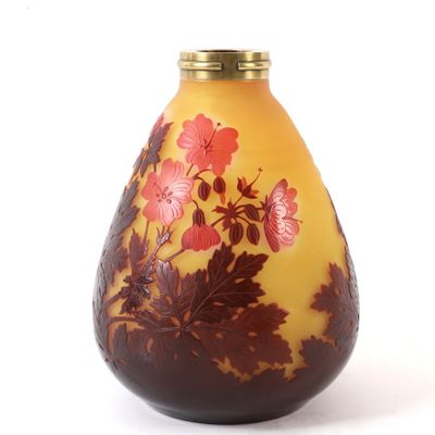 un vase jaune orné de fleurs rouges, posé sur un fond blanc