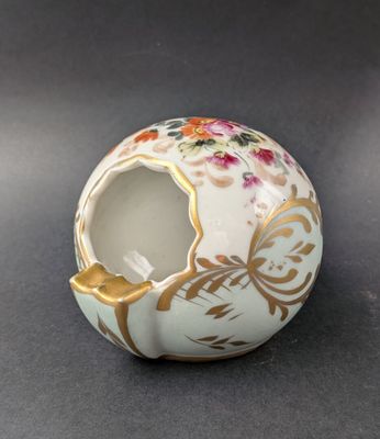 a small white vase with a gold decoration on it