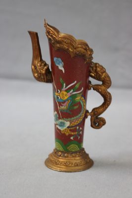 un vase rouge orné d'une poignée en forme de dragon doré