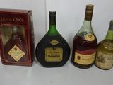 three bottles of liquor sit on a table next to a box of wine