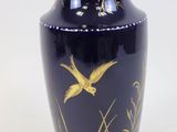 un vase bleu orné de motifs dorés sur un fond blanc
