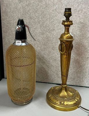 une lampe de table dorée posée à côté d'une bouteille sur une table
