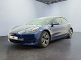 une Tesla Model 3 bleue garée dans une pièce blanche