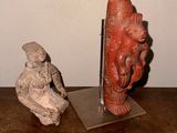two statues on a wooden table with a white wall in the background