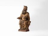 une vieille statue en bois représentant un homme assis sur une chaise