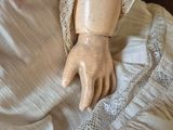 a doll that is laying on a bed with it ' s hands on the pillow