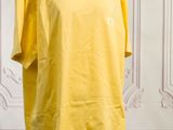 Le t-shirt jaune est posé sur un mannequin devant un mur.