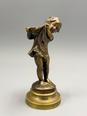 une figurine antique en bronze représentant un garçon sur un socle