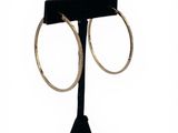 a close up of a pair of gold hoop earrings on a black stand