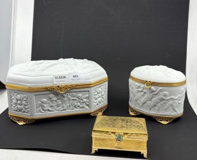 deux boîtes blanches et dorées posées sur une surface noire