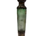 a green glass bottle sitting on top of a wooden base