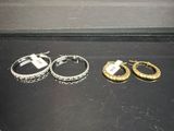 trois paires de boucles d'oreilles en anneau dorées et argentées sur un fond noir