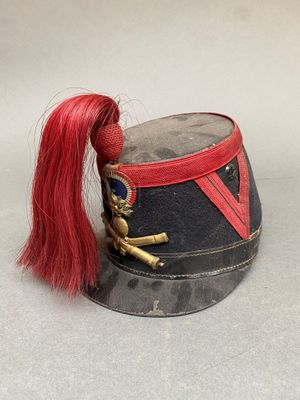 un petit chapeau avec un cheveu rouge et une poupée assise dessus