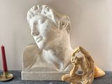 a statue of a man sitting on a table next to a candle