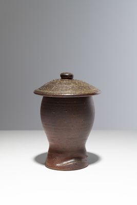 une photo d'un vase marron muni d'un couvercle, posé sur une table