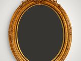 a gold oval mirror hanging on a wall next to a white wall