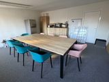 brightly colored chairs sit around a wooden table in an empty room