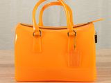 an orange handbag sitting on top of a wooden table
