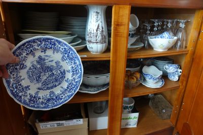 une personne tenant une assiette bleue et blanche devant une armoire