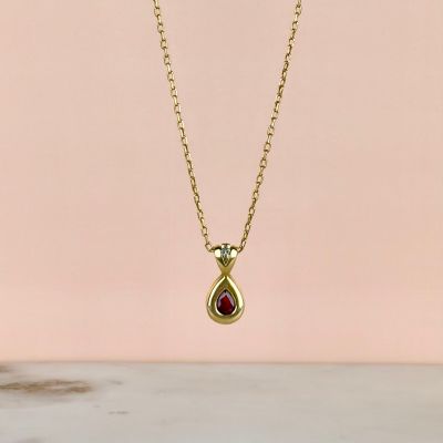 a gold necklace with a tear shaped ruby stone on a gold chain