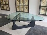 a glass table with a black base on a checkered floor