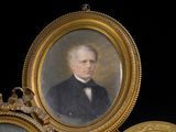 trois portraits encadrés d'hommes en costume-cravate posés sur une table