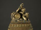 une statue en bronze représentant un homme assis au sommet d'une horloge