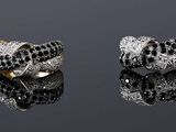 three rings with a gold ring on top of them sitting on a reflective surface