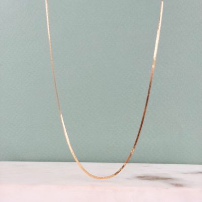 un gros plan d'un collier en or posé sur un comptoir en marbre