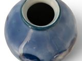 a blue vase with a white rim sitting on a white surface