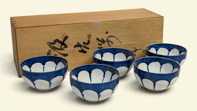 four blue and white bowls sitting in front of a wooden box