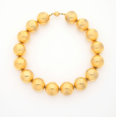 a gold beaded necklace on a white background